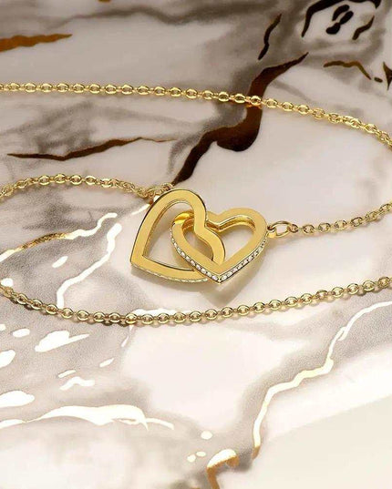 yellow gold interlocking hearts necklace on a marble counter top