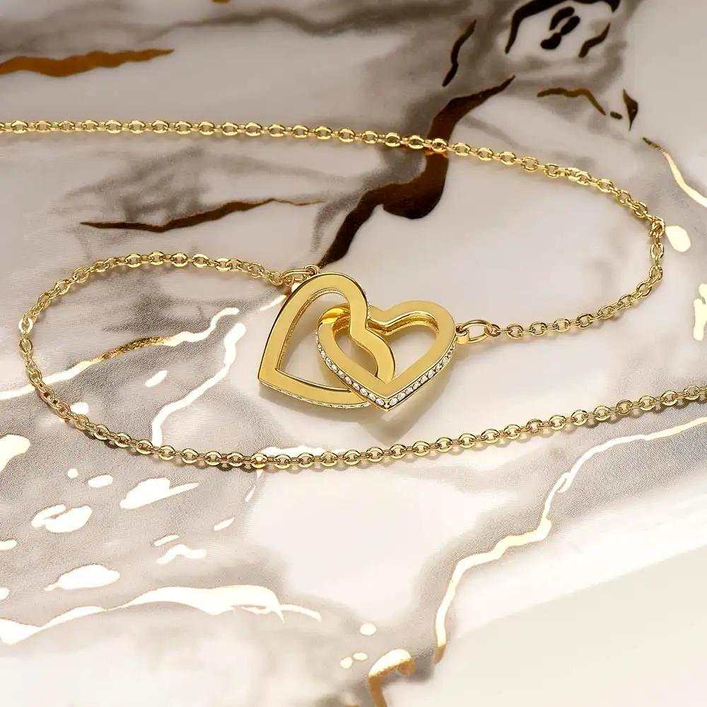 yellow gold interlocking hearts necklace on a marble counter top