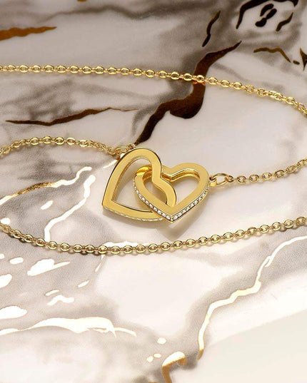 gold interlocking hearts necklace on a marble top