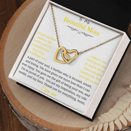 A gold gold interlocking hearts necklace up close on a stump