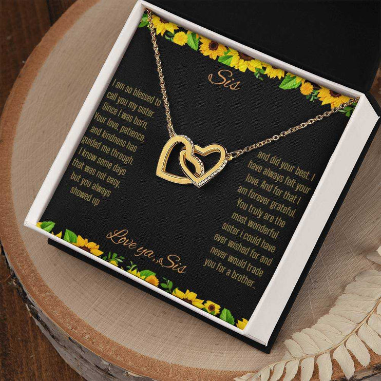 Interlocking Hearts Necklace with a gold on gold variant on a To Sis from Sis greeting card close up in a two-tone box angled to the right side