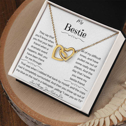 a gold interlocking hearts necklace up close on a stump
