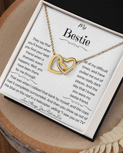 a gold interlocking hearts necklace up close on a stump