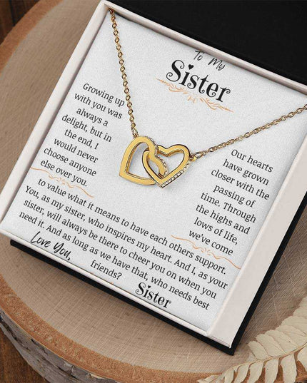 a yellow gold interlocking hearts necklace up close on a stump
