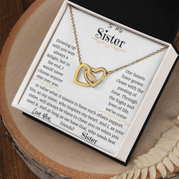 a yellow gold interlocking hearts necklace up close on a stump