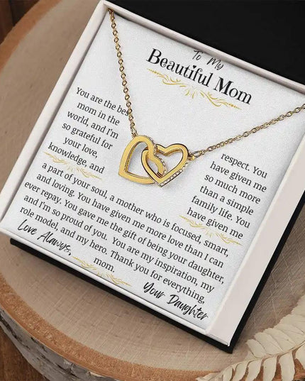 a yellow gold interlocking hearts necklace on a stump