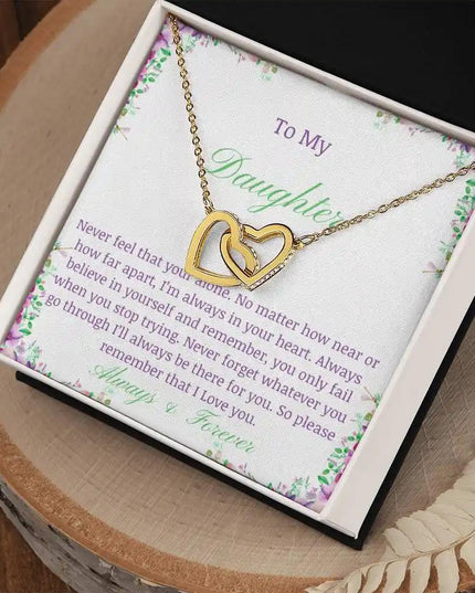 a gold interlocking hearts necklace up close on a stump
