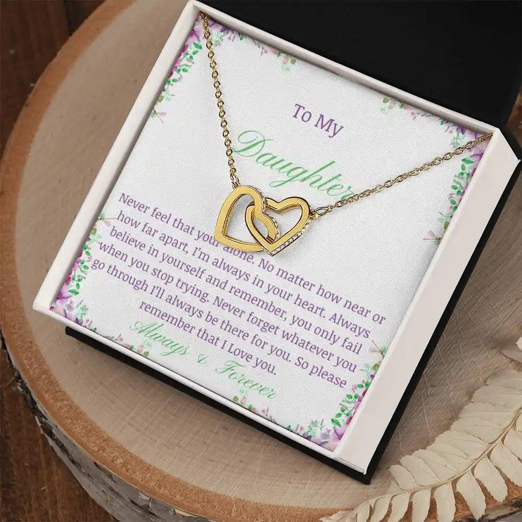 a gold interlocking hearts necklace up close on a stump