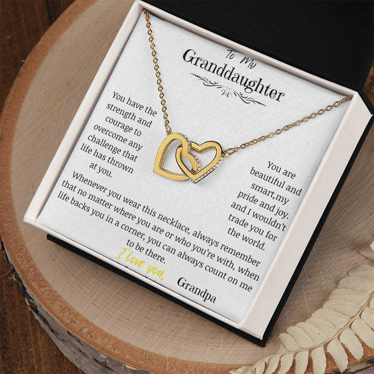 A yellow gold interlocking hearts necklace on a stump