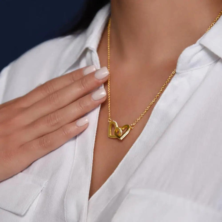 gold interlocking hearts necklace on model's neck