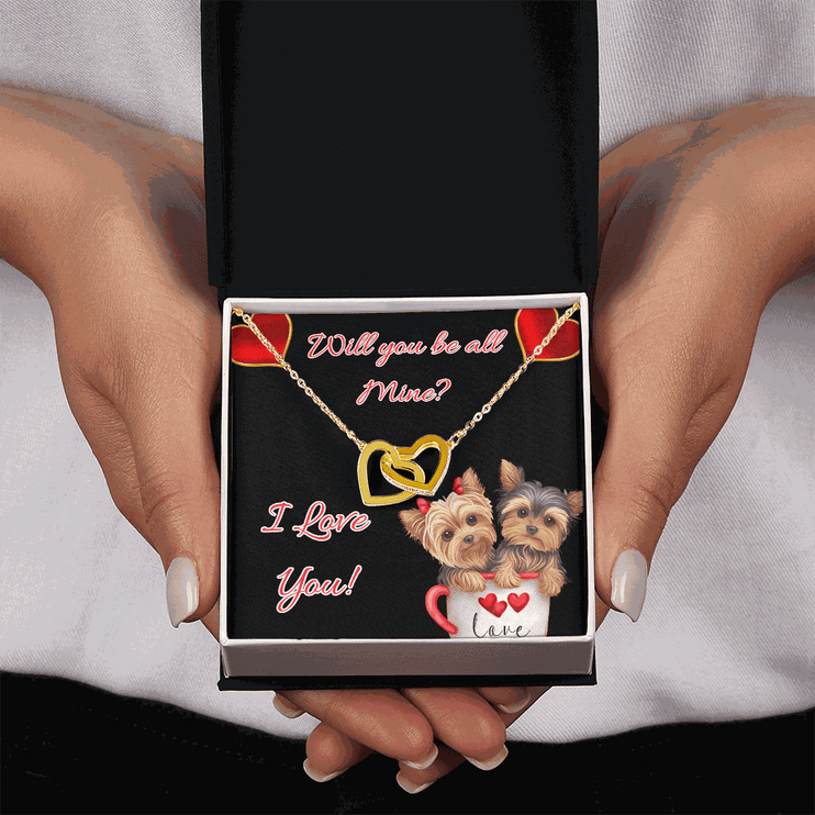 gold interlocking hearts necklace in a soft box in a model's hands