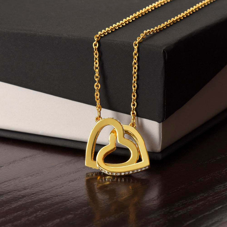 18k interlocking hearts necklace on top of closed soft box