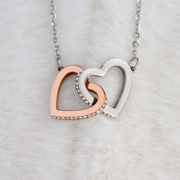 rose gold interlocking hearts necklace on a marble top backdrop