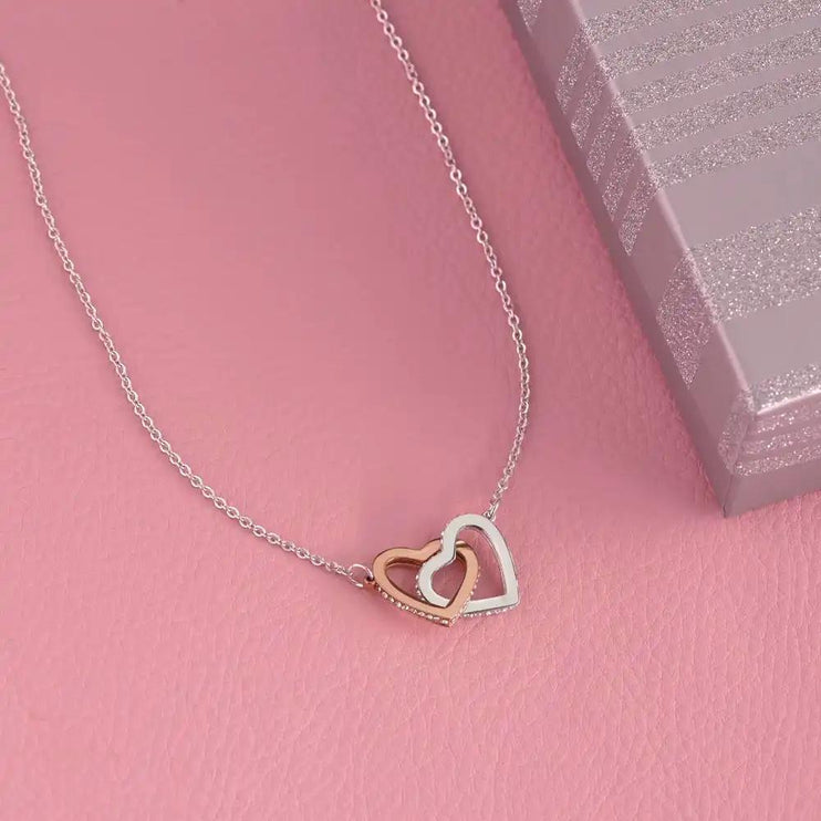 rose gold interlocking hearts necklace on a pink background