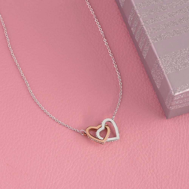 rose gold interlocking hearts necklace on a pink display table