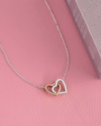 rose gold interlocking hearts necklace on a pink cloth