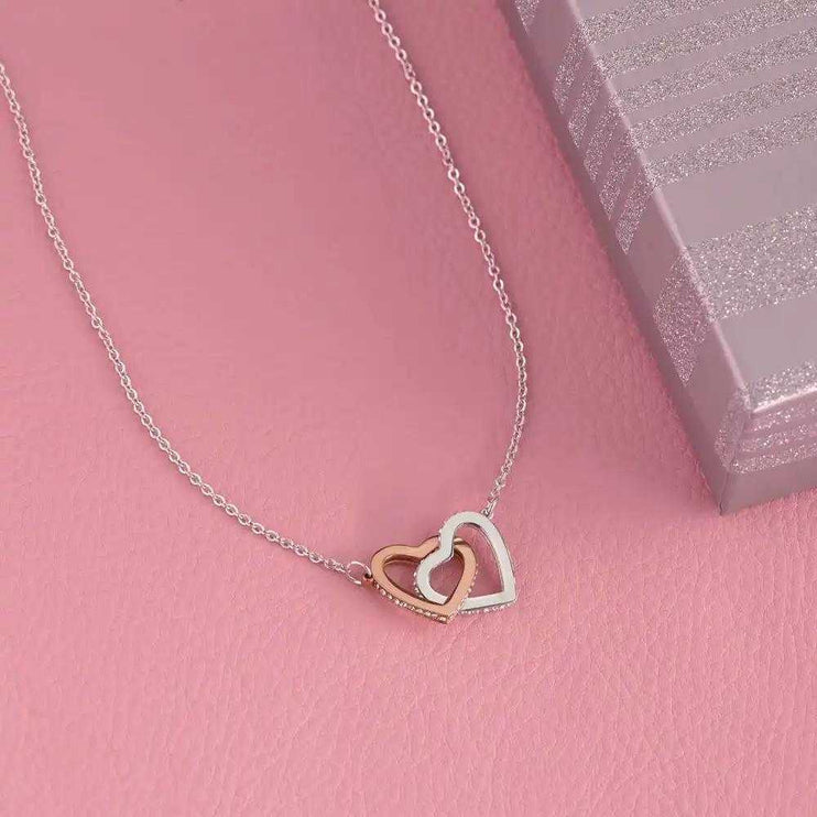 rose gold interlocking hearts necklace on a pink table