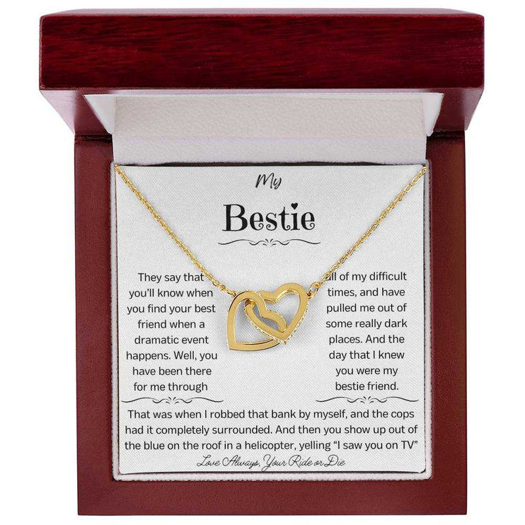 a gold interlocking hearts necklace up close in a mahogany box