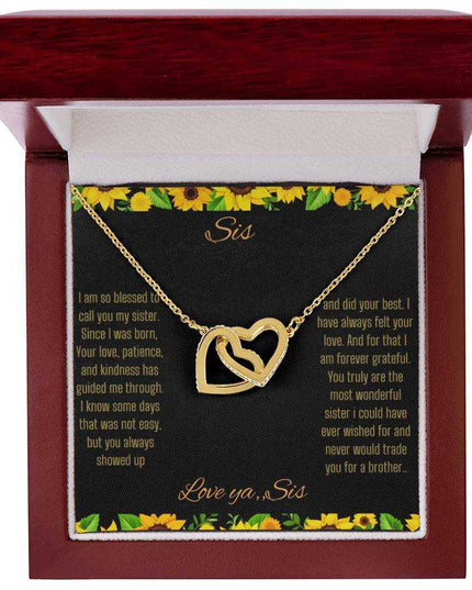 Interlocking Hearts Necklace with a gold on gold variant on a To Sis from Sis greeting card close up in a mahogany box