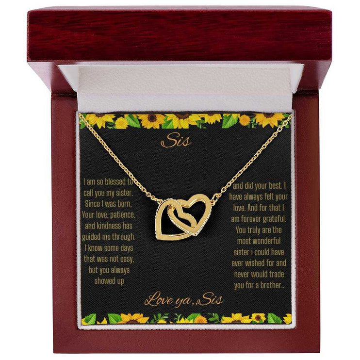 Interlocking Hearts Necklace with a gold on gold variant on a To Sis from Sis greeting card close up in a mahogany box