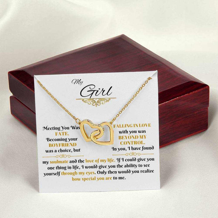 gold interlocking hearts necklace on a message card beside a closed luxury box