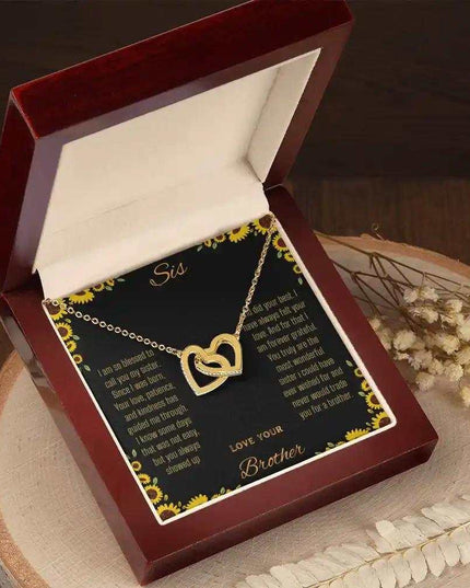 Interlocking Hearts Necklace with a gold variant on a To Sis from Brother greeting card inside a mahogany box sitting on a stump angled to right side