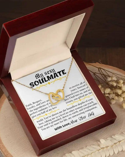 a yellow gold interlocking hearts necklace in a mahogany box on stump