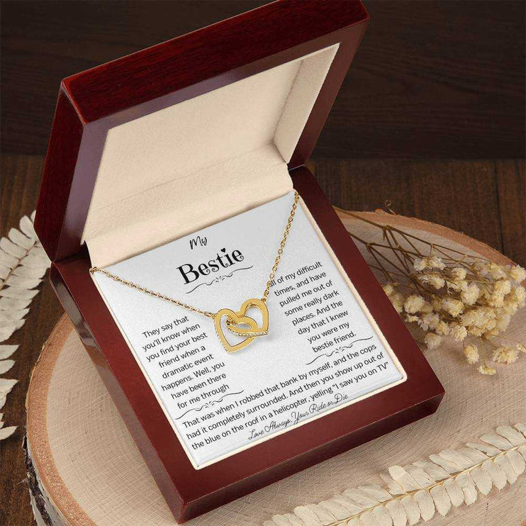a gold interlocking hearts necklace in a mahogany box on a stump