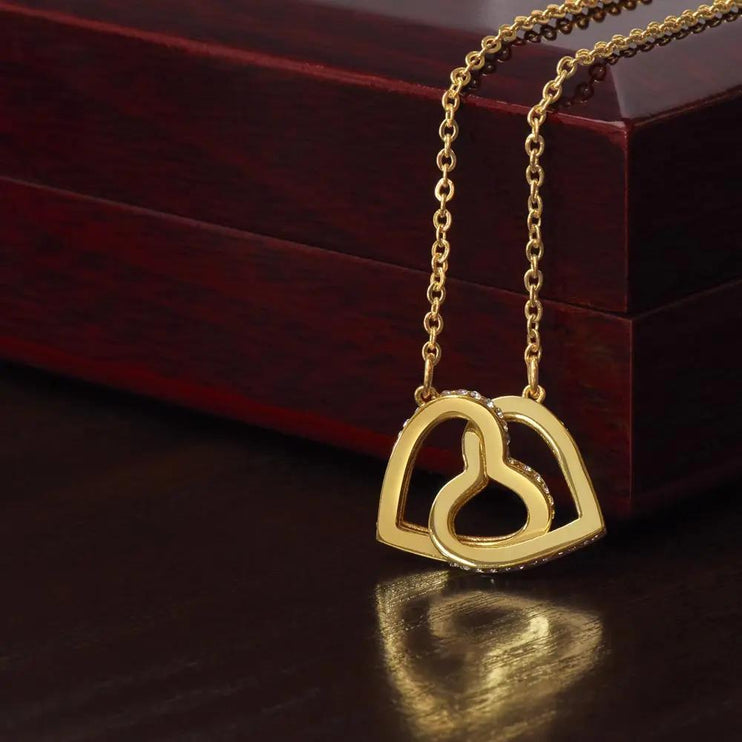 yellow gold interlocking hearts necklace on top of mahogany box