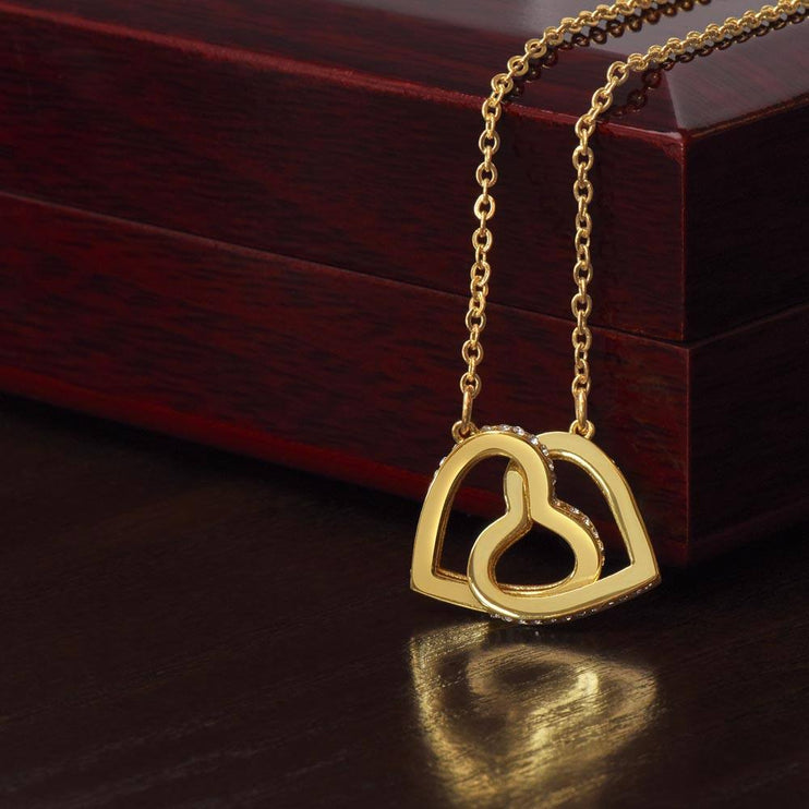 18k interlocking hearts necklace on top of a closed luxury box