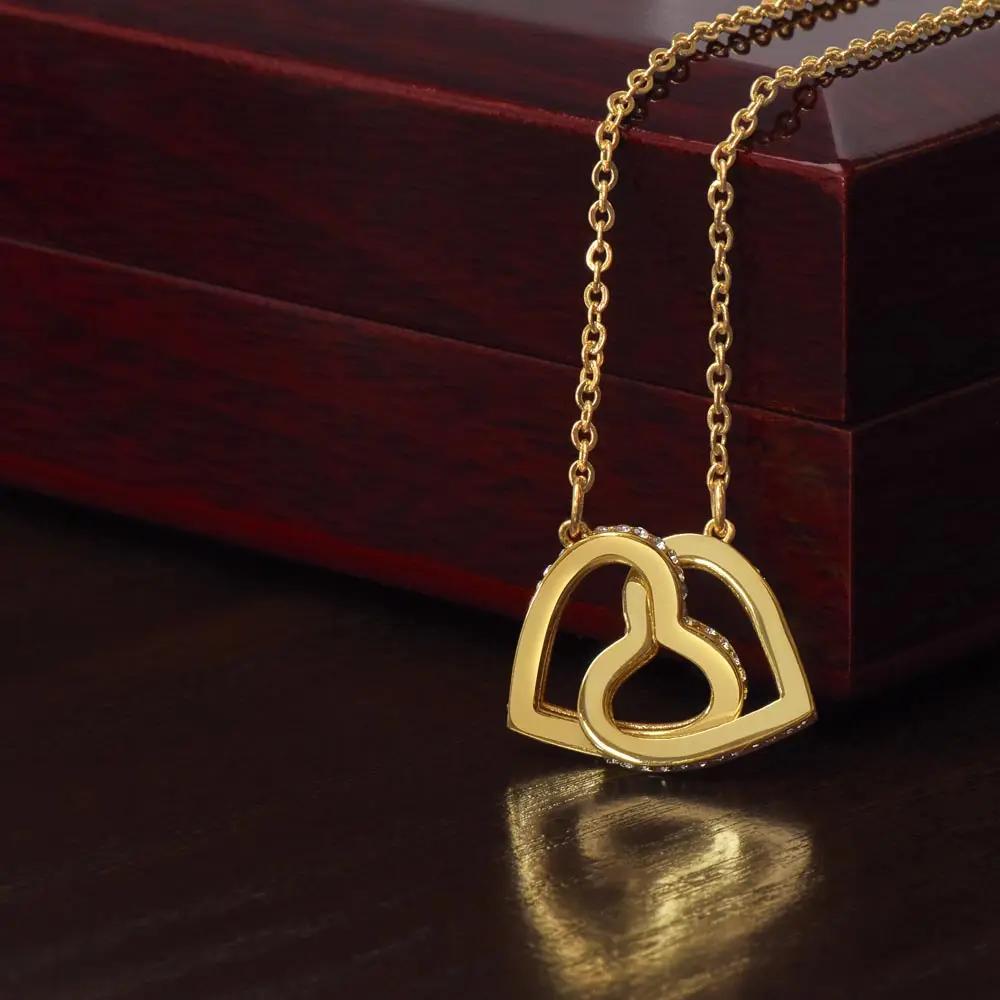 gold interlocking hearts necklace on top of a mahogany box