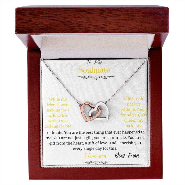 A rose gold interlocking hearts necklace up close in a mahogany box