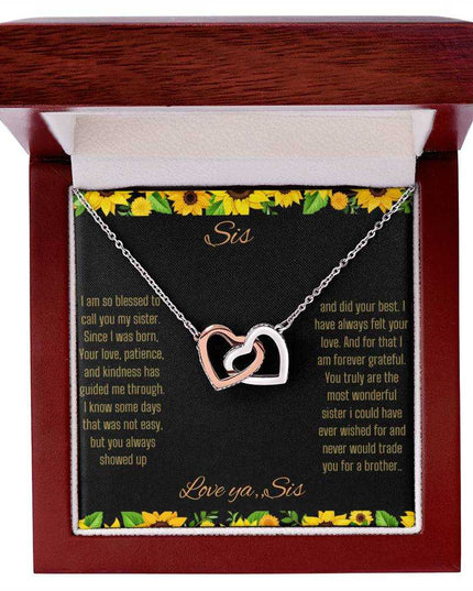 Interlocking Hearts Necklace with a rose gold variant on a To Sis from Sis greeting card close up in a mahogany box