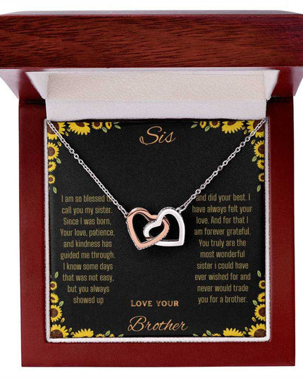 Interlocking Hearts Necklace with rose gold variant on a To Sis from Brother greeting card inside a mahogany box up close