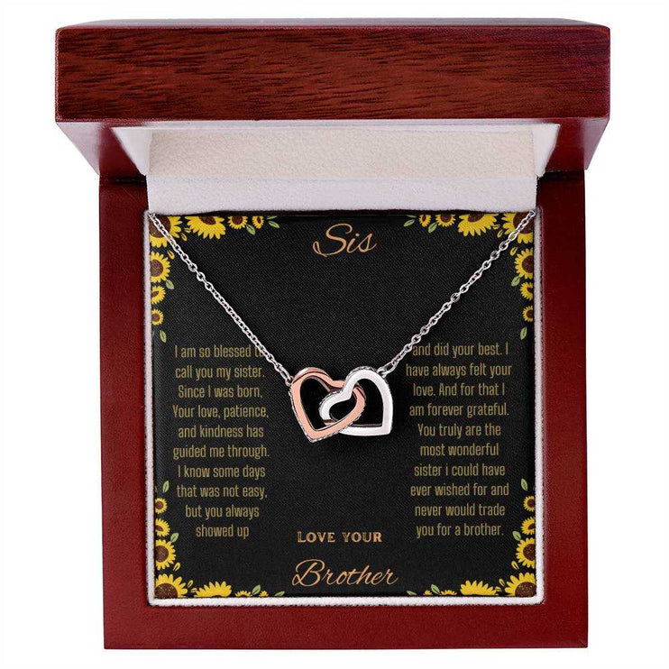 Interlocking Hearts Necklace with rose gold variant on a To Sis from Brother greeting card inside a mahogany box up close