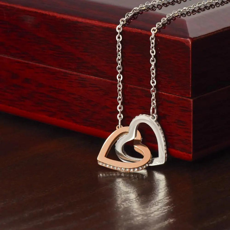 rose gold interlocking hearts necklace on a mahogany box