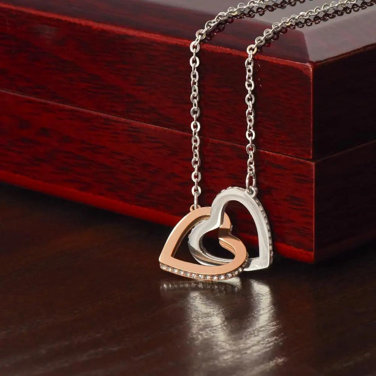 rose gold interlocking hearts necklace on top of mahogany box