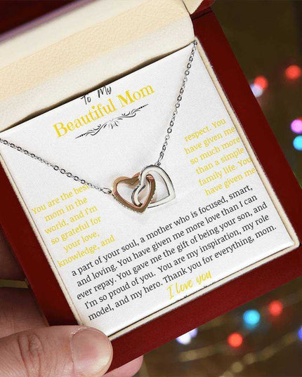 A rose gold interlocking hearts necklace up close in a mahogany box angled to the left