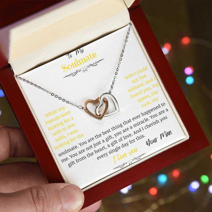 A rose gold interlocking hearts necklace up close in a mahogany box on a angle