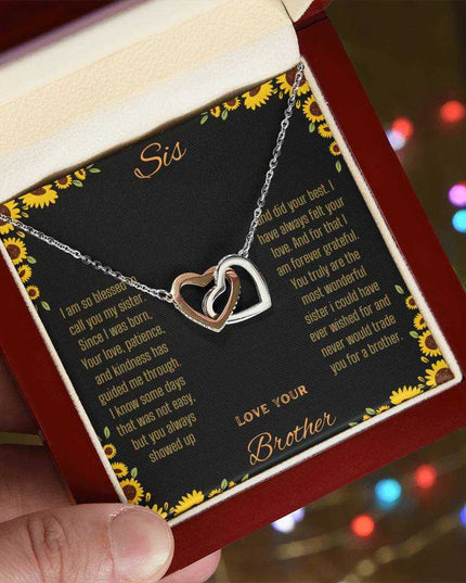 Interlocking Hearts Necklace with rose gold variant on a To Sis from Brother greeting card up close in models hand angled to right side