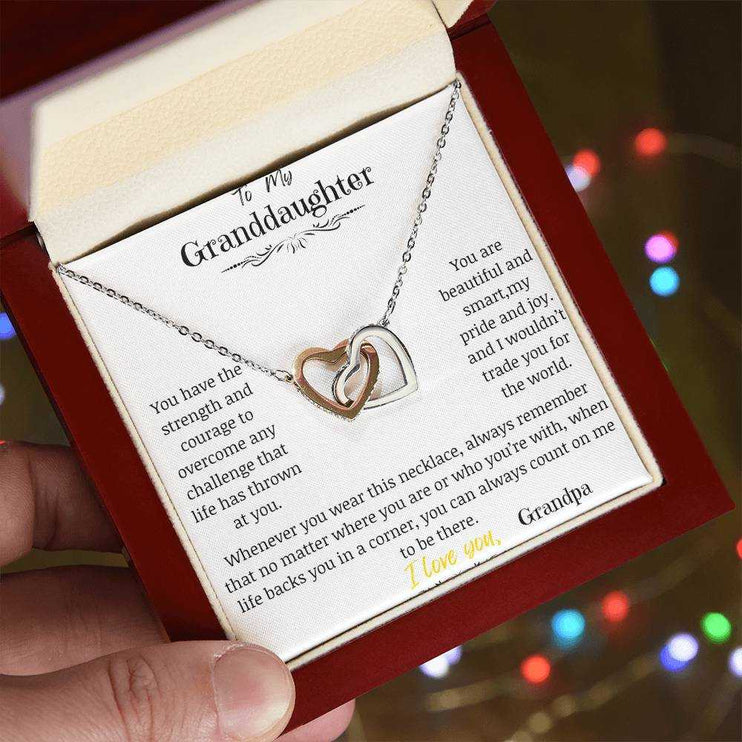 A rose gold interlocking hearts necklace in a mahogany box angled to the left