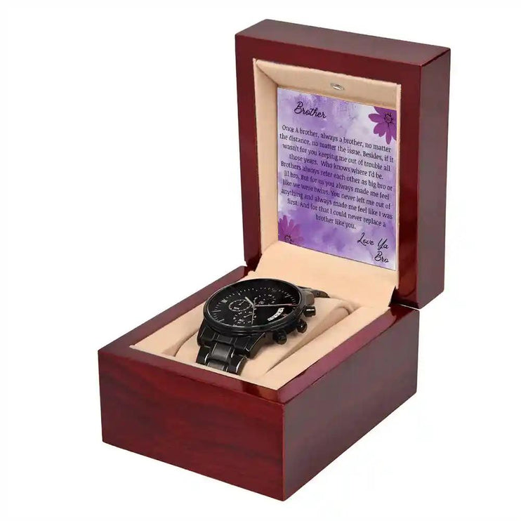 A men's chronograph watch in a mahogany box with a to brother card angled to the right.