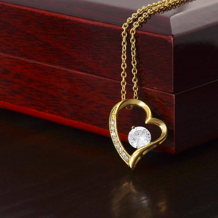 a yellow gold forever love necklace on a mahogany box