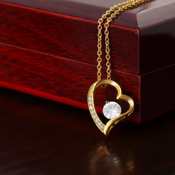 a yellow gold forever love necklace on a mahogany box