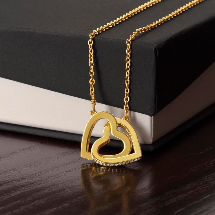 Interlocking Hearts necklace with gold variant hanging on a closed two-tone box