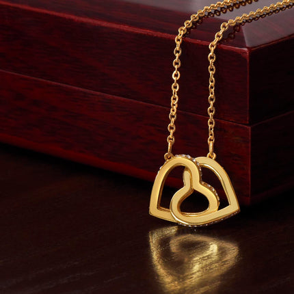Heart necklaceInterlocking Hearts necklace with gold variant hanging on a closed mahogany box