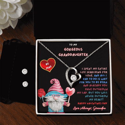 white gold forever love necklace earring set on left side of soft box with flowers