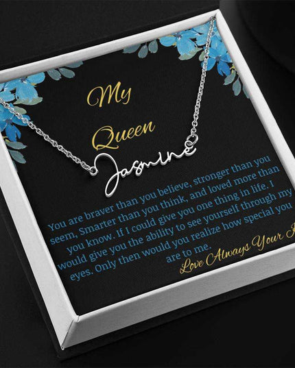 A polished stainless-steel signature name necklace in a two-tone box with a to my queen greeting card angled to the left