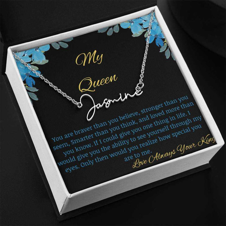 A polished stainless-steel signature name necklace in a two-tone box with a to my queen greeting card angled to the left