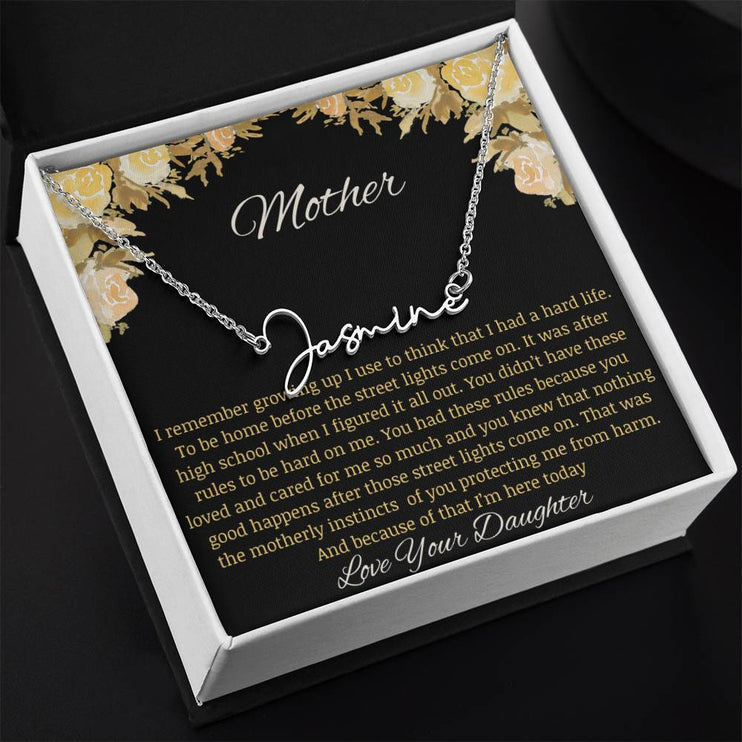 A polished stainless-steel signature name necklace in a two-tone box.